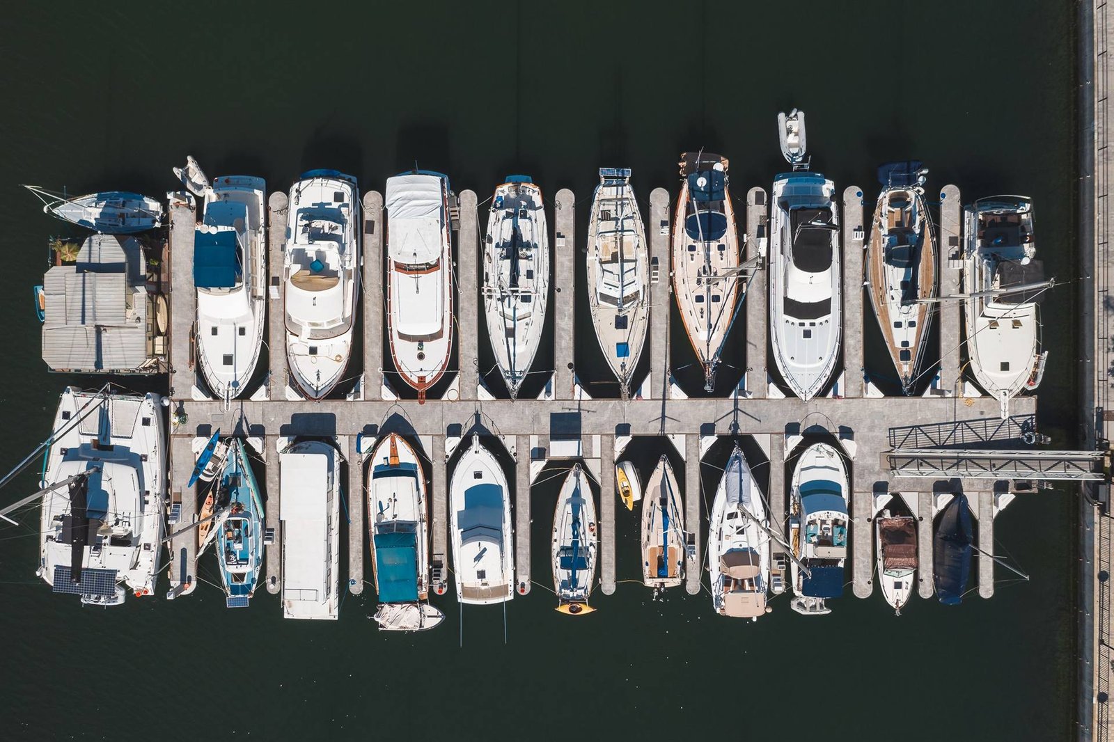 Aerial view of yachts and sailboats moored in neat rows along a marina pontoon