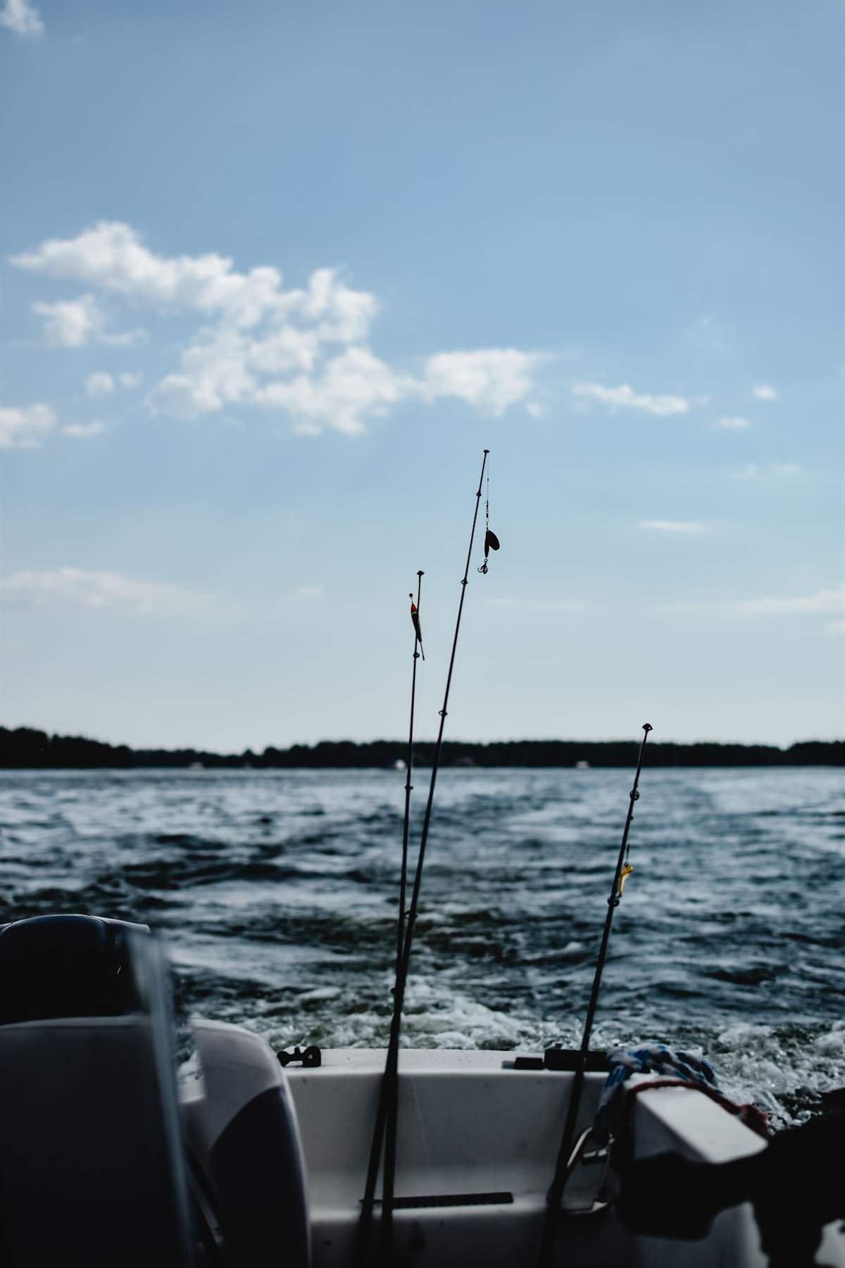 Fishing rods in the stern of a boat under way, wake trailing across open water