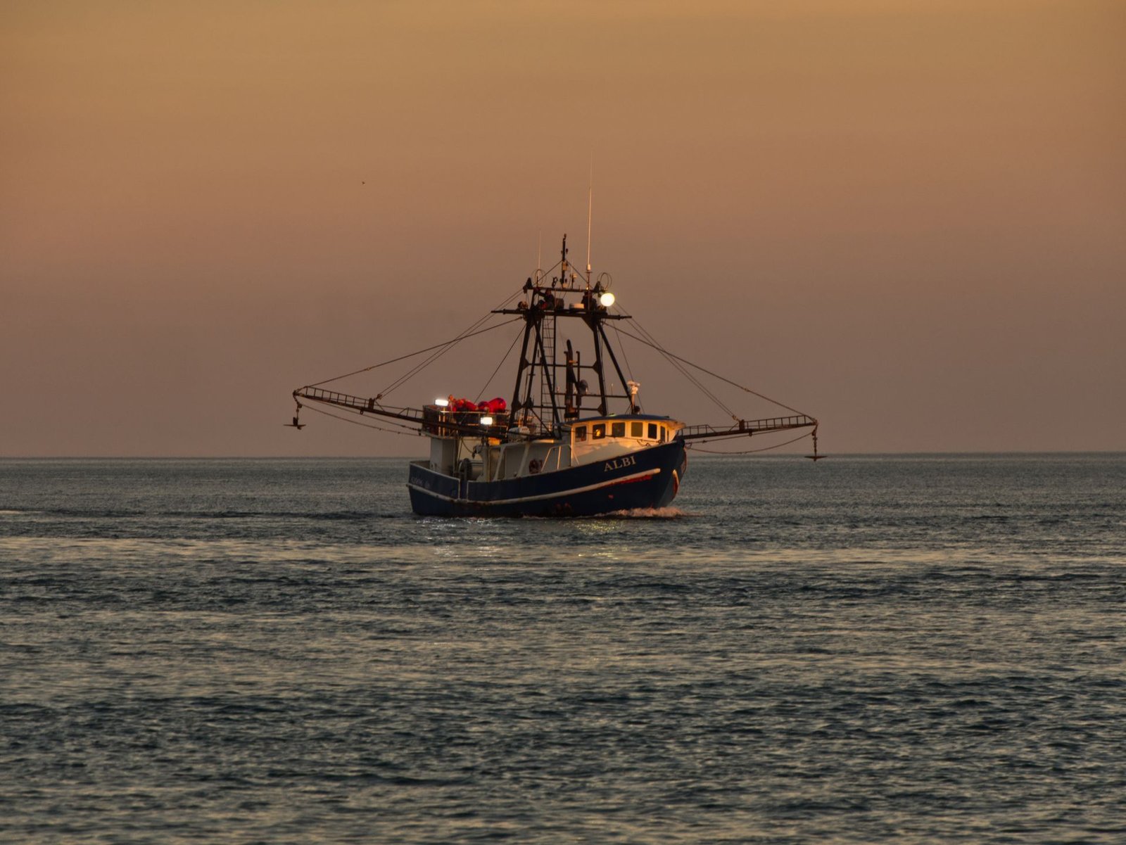 Fishing trawler working offshore at sunset