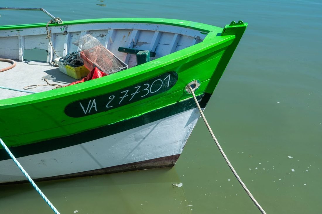 Green and white wooden fishing boat moored in harbour